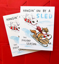 Load image into Gallery viewer, Hanging On By A Sled Winter Sledding Holiday Card
